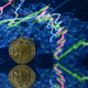 A gold plated souvenir cryptocurrency Tether (USDT) coin arranged beside a screen displaying a trading chart.